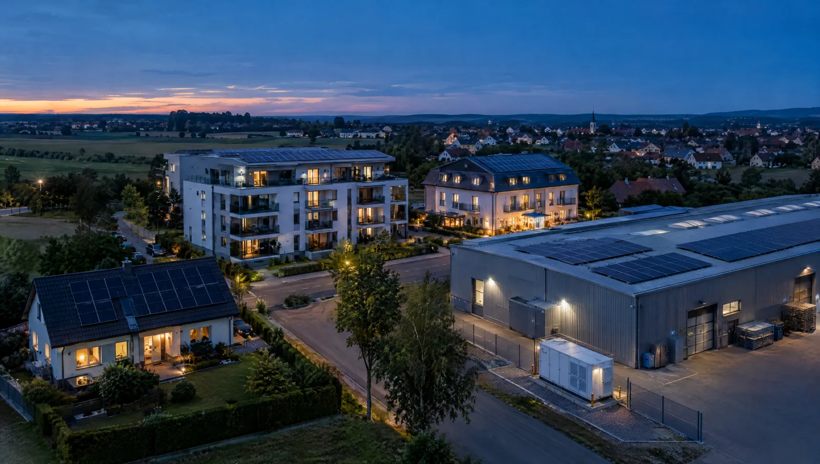 Rodinný dům, bytový dům, hotel a výrobní hala s fotovoltaikou na střechách při soumraku, pohled z dronu